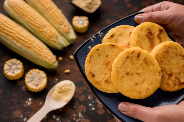 Manos de primer plano sosteniendo plato de arepas