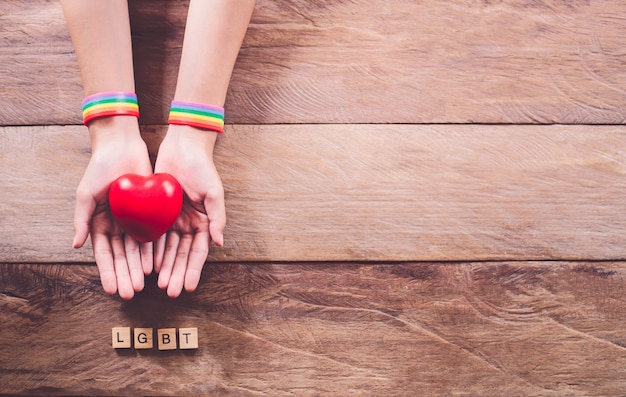 Manos con una pulsera de color arcoíris Colocadas sobre un piso de madera. Lucha por los derechos de los homosexuales. Concepto de orgullo gay LGBT