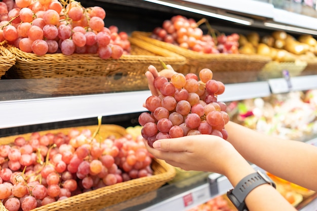 Manos que están recogiendo frutas y verduras de la estantería para seleccionar calidad.