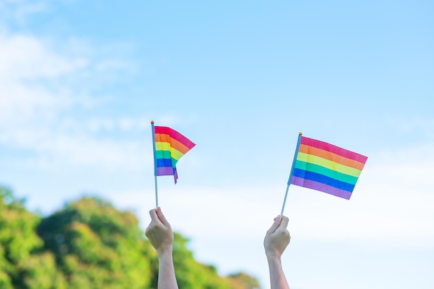 Manos que muestran la bandera del arco iris LGBTQ en el fondo de la naturaleza Apoyo a la comunidad lesbiana, gay, bisexual, transgénero y queer y al concepto del mes del orgullo