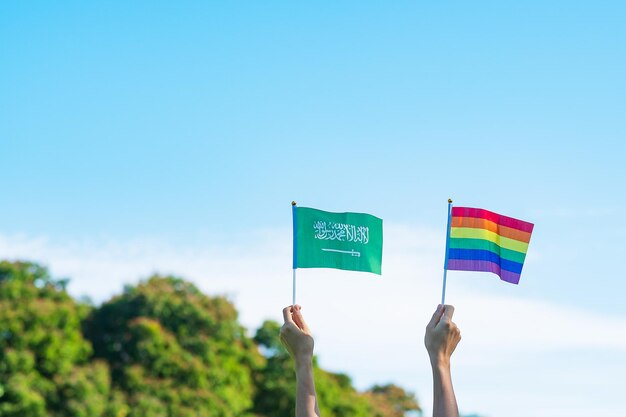 Manos que muestran la bandera LGBTQ Rainbow y Arabia Saudita en el fondo de la naturaleza Apoyar a la comunidad lesbiana gay bisexual transgénero y queer y el concepto del mes del orgullo