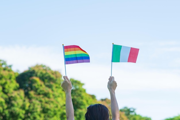 Manos que muestran la bandera LGBTQ Rainbow e Italia en el fondo de la naturaleza Apoyar a la comunidad lesbiana gay bisexual transgénero y queer y el concepto del mes del orgullo