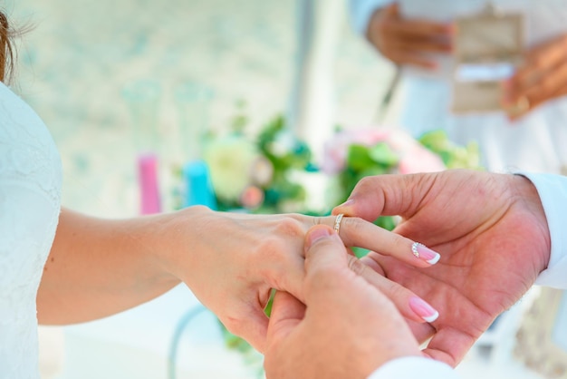 Manos de los recién casados en la ceremonia de boda de vestir los anillos de boda