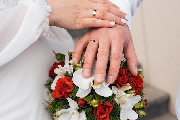 Manos de los recién casados en un concepto de ramo de novia de rosas y orquídeas para agencias