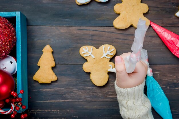Foto manos recortadas decorando galletas en la mesa