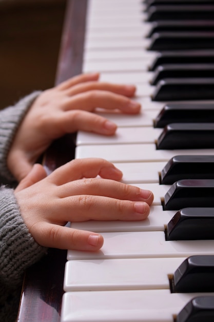 Manos recortadas de niño tocando el piano antiguo