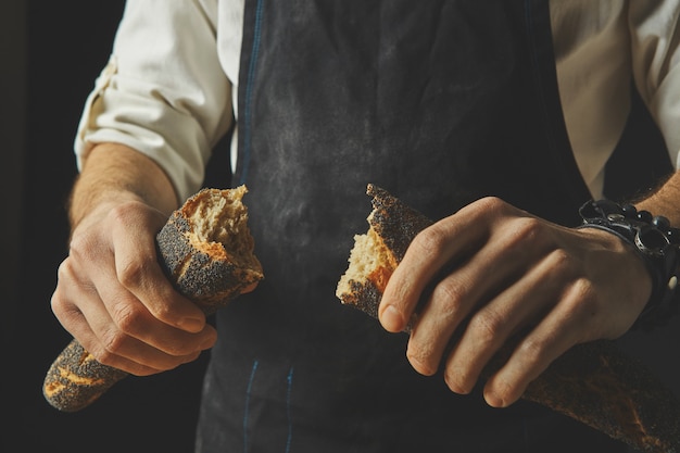 Manos rompiendo y separando baguette orgánico fresco