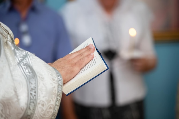 Las manos de un sacerdote ortodoxo con sotana sostienen una Biblia