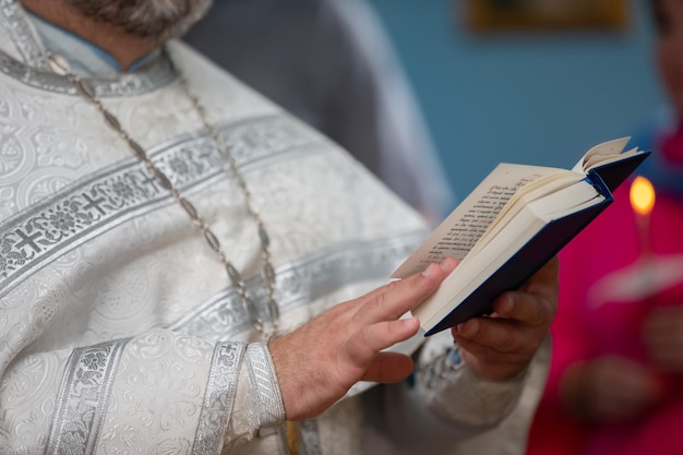 Las manos de un sacerdote ortodoxo con una sotana sostienen una Biblia