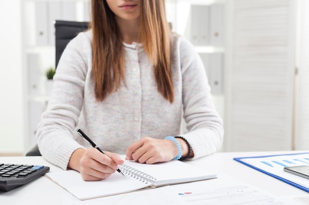 Manos de secretaria escribiendo en un cuaderno