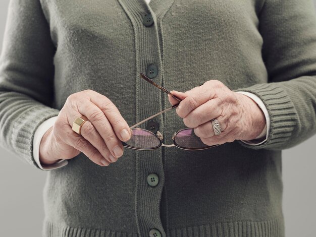 Foto las manos de la señora mayor sosteniendo gafas concepto de envejecimiento de cerca