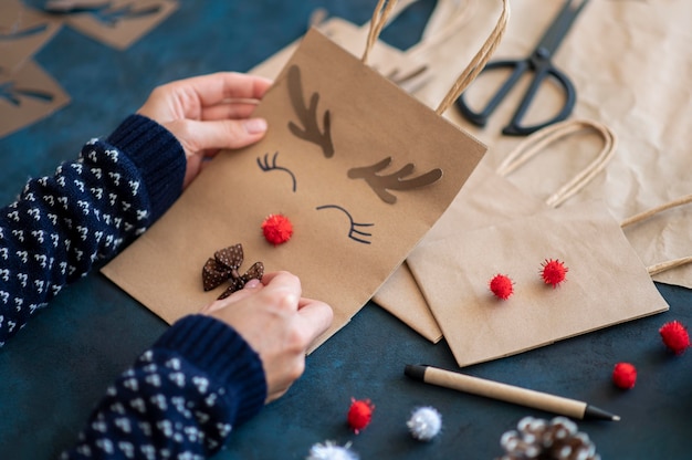 Foto manos sosteniendo adorable reno decorado bolsa de papel de navidad
