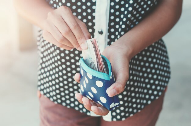 Manos sosteniendo billetes bancarios y pequeña bolsa de dinero