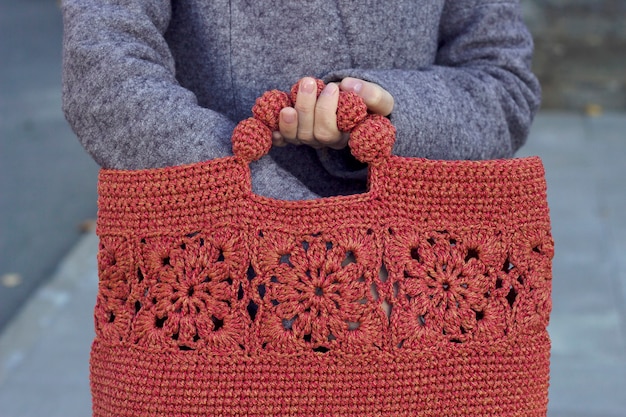 Foto manos sosteniendo una bolsa de punto roja ropa de abrigo y accesorios para la temporada de frío compras de temporada