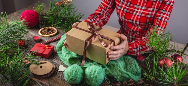 Manos sosteniendo una caja de regalo en un suéter acogedor