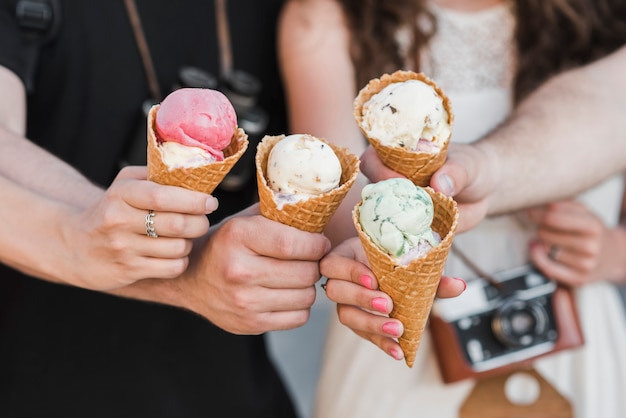 Manos sosteniendo conos de helado