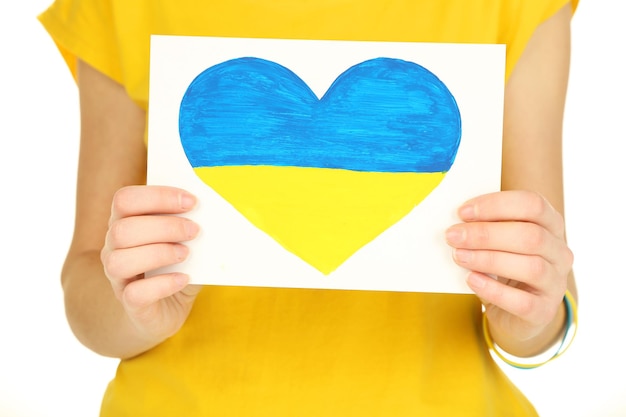 Manos sosteniendo un corazón de papel con la bandera de Ucrania pintada aislada en blanco