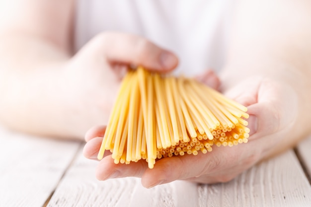 Manos sosteniendo espagueti en la cocina