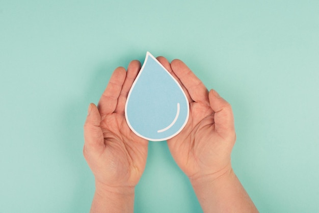 Manos sosteniendo una gota de agua, corte de papel, problema ambiental, espacio de copia para texto