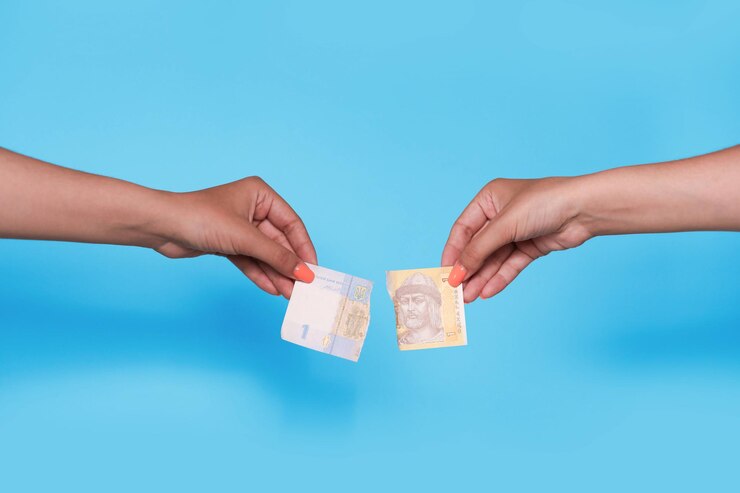 Manos sosteniendo hryvnia ucraniana destrozada