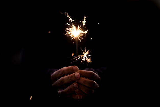 Manos sosteniendo la luz de bengala. Celebración de año nuevo y navidad