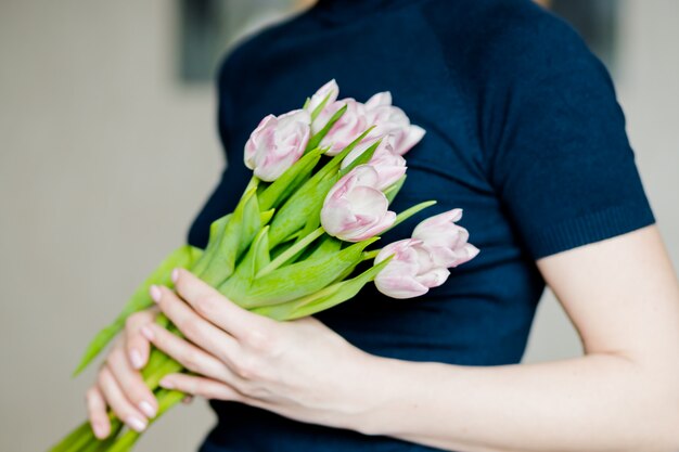 Manos sosteniendo un ramo de tulipanes blancos frescos. Ramo de flores de primavera en sus manos.