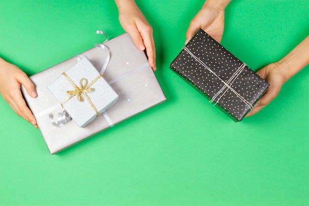 Manos sosteniendo regalos envueltos en papel de regalo en verde claro