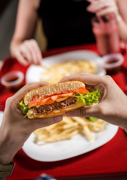 manos sosteniendo sándwich en el ambiente del restaurante concepto de comida rápida