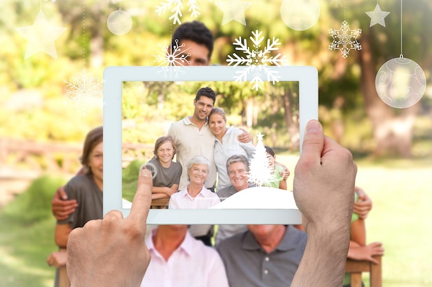 Foto manos sosteniendo tablet pc contra la familia en el parque