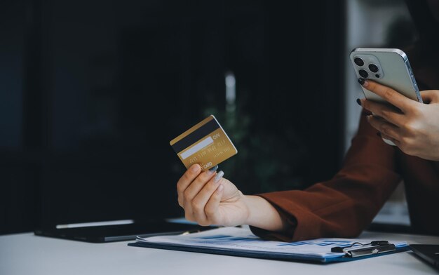 Manos sosteniendo una tarjeta de crédito de plástico y usando una computadora portátil Concepto de compras en línea Imagen tonada