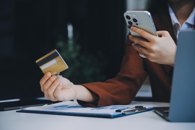 Manos sosteniendo una tarjeta de crédito de plástico y usando una computadora portátil Concepto de compras en línea Imagen tonada