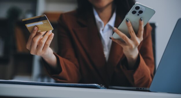 Manos sosteniendo una tarjeta de crédito de plástico y usando una computadora portátil Concepto de compras en línea Imagen tonada