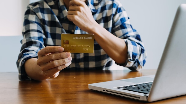 Manos sosteniendo una tarjeta de crédito y usando una computadora portátil Compras en línea