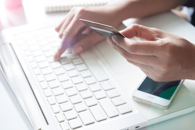 Manos sosteniendo tarjeta de crédito y usando laptop. Las compras en línea