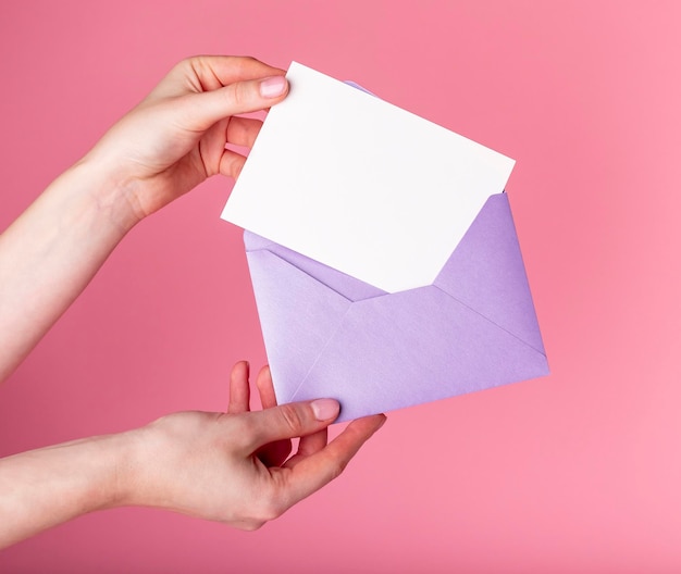 Manos sosteniendo una tarjeta de felicitación en blanco en un sobre concepto de día de San Valentín carta de amor o invitación de vacaciones