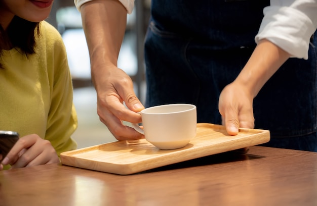 manos sosteniendo una taza de café para el cliente en la cafetería.