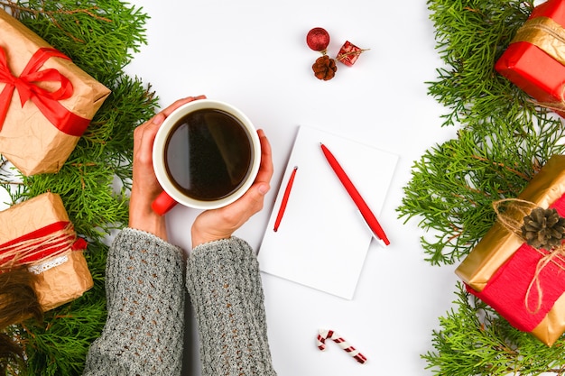 Manos sosteniendo una taza de café sobre un fondo de Navidad