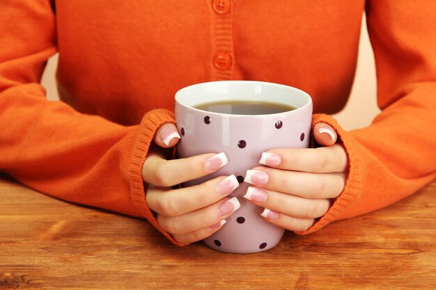 Manos sosteniendo la taza de primer plano de bebida caliente