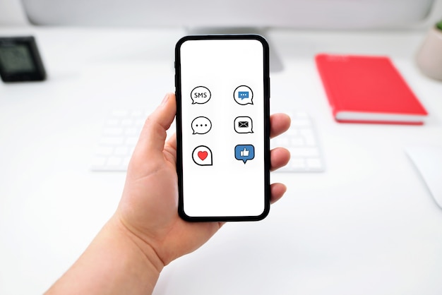 Manos sosteniendo el teléfono con la aplicación messenger en la pantalla sobre una mesa en la oficina