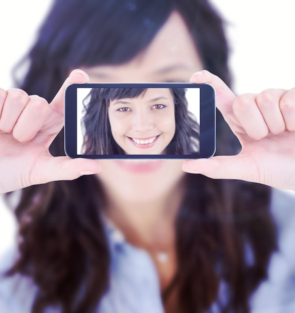 Manos sosteniendo el teléfono inteligente contra el retrato de una mujer joven sonriente