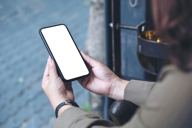 manos sosteniendo un teléfono móvil negro con pantalla de escritorio en blanco