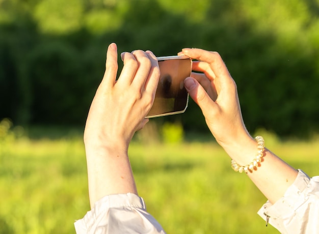 Manos sosteniendo el teléfono móvil tomando fotos grabando video en la naturaleza