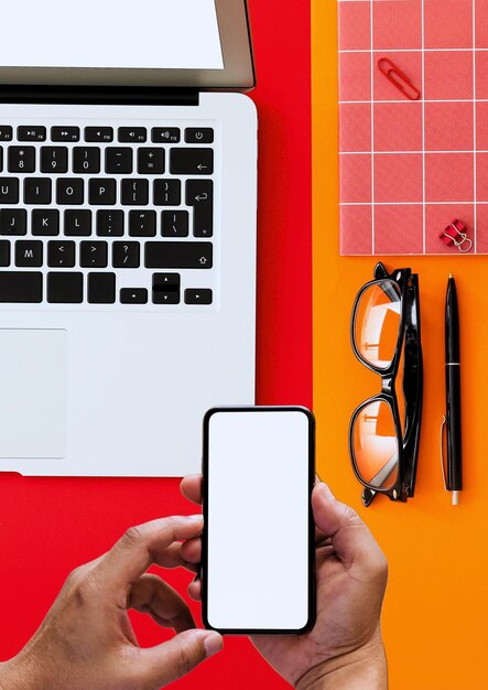 Manos sosteniendo teléfonos celulares pinzas de ropa notas portátiles con combinación de fondo rojo y amarillo