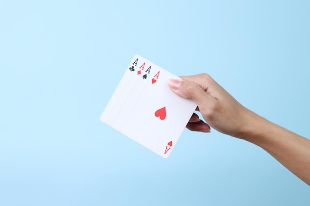 Las manos sostienen las cartas de póquer de mano con fondo azul aislado