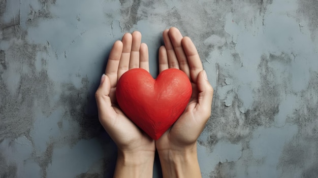 las manos sostienen un corazón transparente rojo brillante sobre un fondo de cemento mínimo