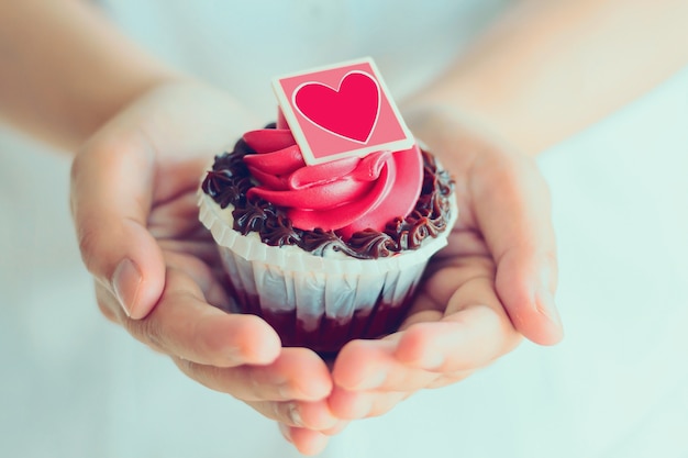 Manos sostienen cupcake de San Valentín