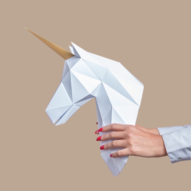 Las manos sostienen un modelo de papercraft 3d blanco de Unicornio