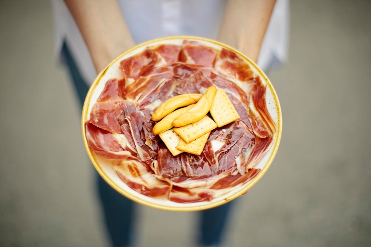 Foto manos sostienen plato de pan y jamón ibérico