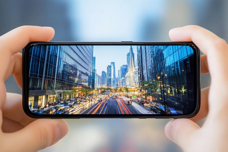 Las manos sostienen un teléfono inteligente que muestra un paisaje urbano vibrante y tráfico en movimiento al anochecer