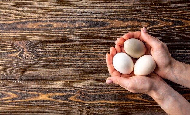 Foto las manos sostienen tres huevos orgánicos crudos con cáscaras de diferentes colores inusuales